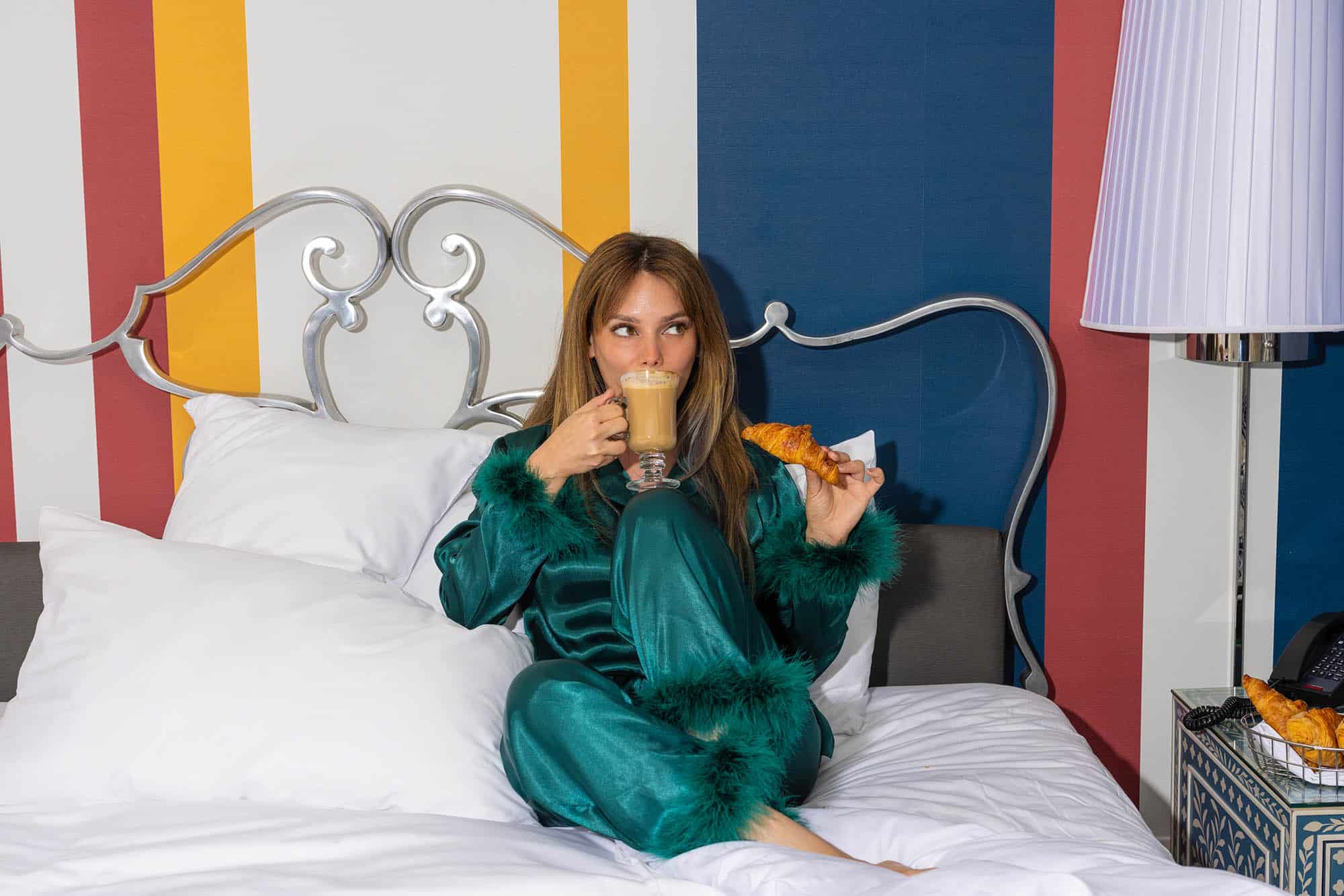 A woman enjoying a cup of coffee and a croissant at The Marker