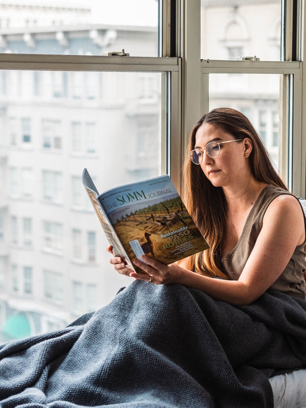 A woman reading a magazine sitting next to a window at The Marker