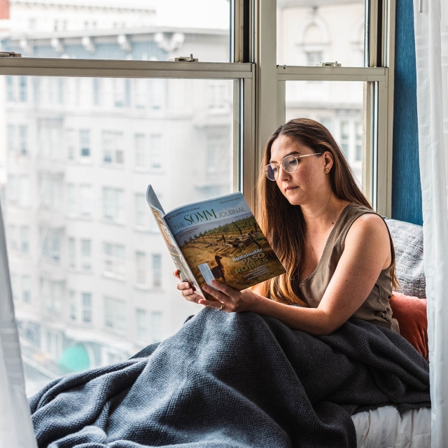A woman reading a magazine sitting next to a window at The Marker