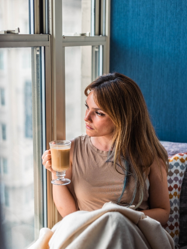 A guest staying at The Marker holding a cup of coffee while looking out the window