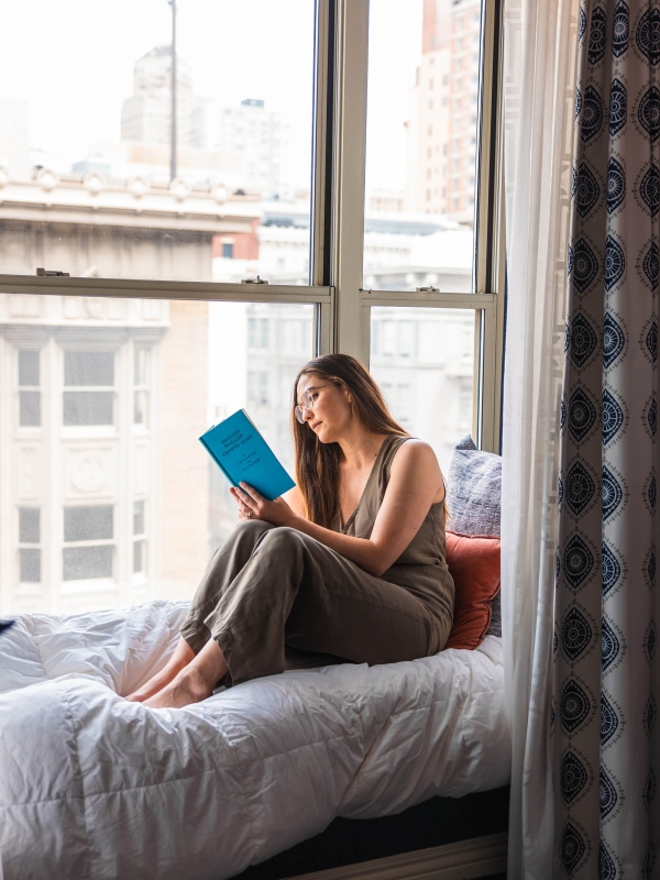 A woman reading a book while sitting in a room at The Marker