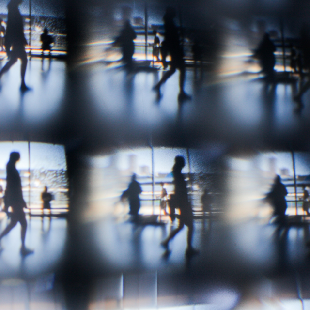 Abstract, mirrored image of silhouetted figures walking, fragmented into a repeating grid pattern