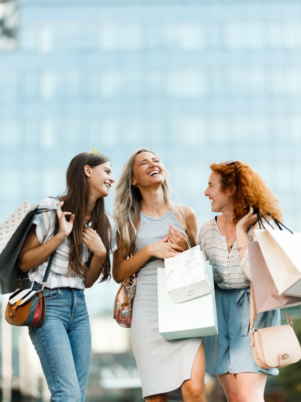 a group of women laughing while holding shopping bags
