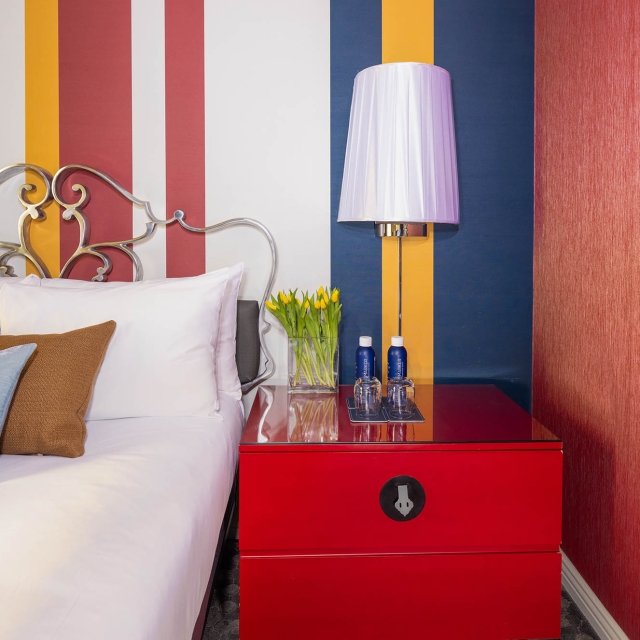 Close up of a red night stand next to a bed at The Marjer